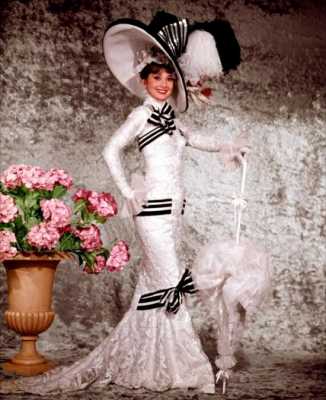 Одри Хепберн в неповторимом белом платье до пола с черными вставами и шлейфом, образ дополняет огромная шляпа