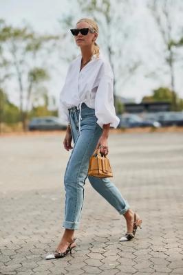 Девушка в подвернутый джинсах, белой блузке и туфлях с открытой пяткой