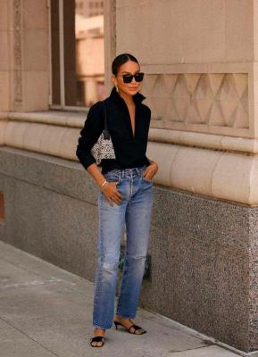 Девушка в простых прямых джинсах, черной рубашке и босоножках на невысоком каблуке