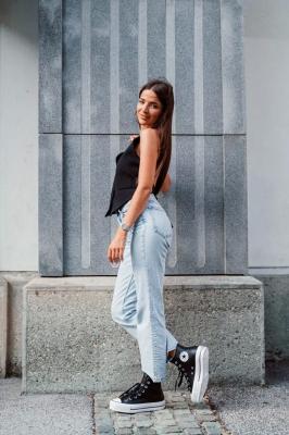 Девушка в светлых джинсах, черном топе и высоких кедах на платформе