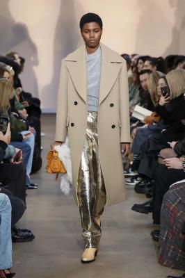 Модель в серебряных брюках, сером свитере и пальто