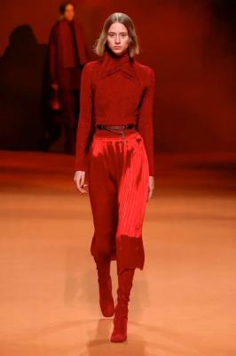 Модель в атласной юбке миди, облегающей водолазке и красных сапогах из замши от Hermès
