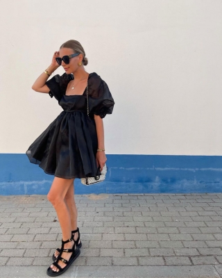 Девушка в пышном черном платье с рукавами и черных сандалиях