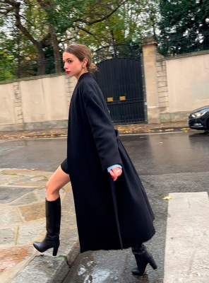Девушка в длинном черном пальто и кожаных сапогах
