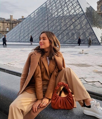 Девушка в бежевом пальто и брюках, образ дополняет мягкая небольшая сумочка коричневого цвета