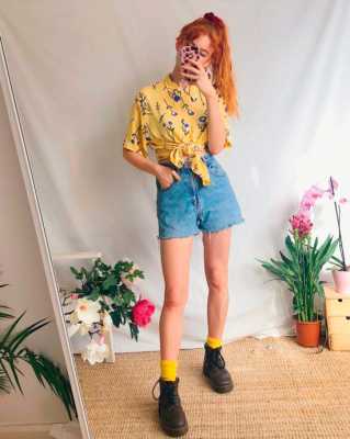Девушка в джинсовых шортах с высокой талией, желтая рубашка с цветочным принтом и ботинки на шнуровке