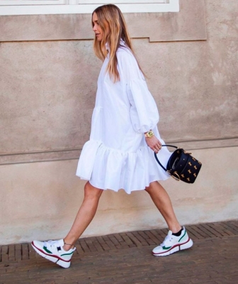 Девушка в белом просторном платье, белые кроссовки с цветными вставками