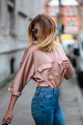 Девушка в простых джинсах с завышенной талией, нежная розовая рубашка из атласа, образ завершают солнцезащитные очки